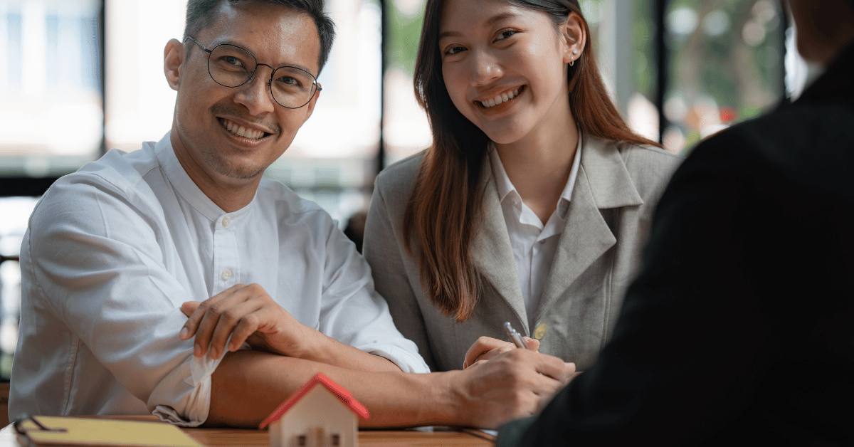 Couple souriant signant un contrat immobilier en agence