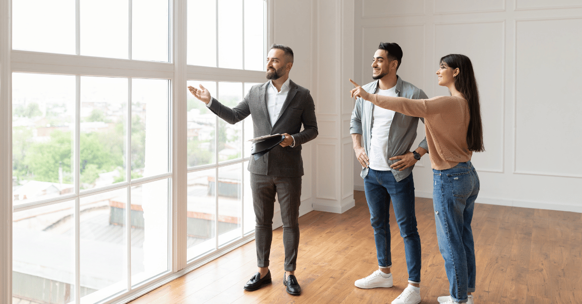 Couple visitant un appartement lumineux avec agent immobilier