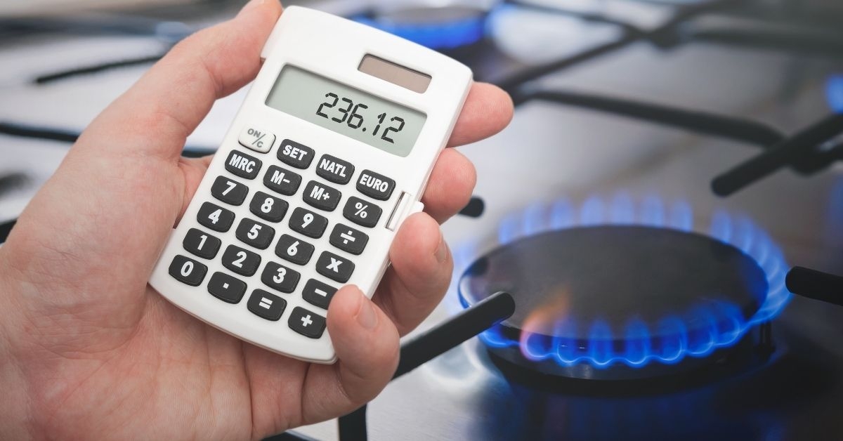 Cuisine d'un appartement avec une cuisinière à gaz et une calculatrice, illustrant l'impact de la hausse du prix du gaz sur le budget des ménages endettés.
