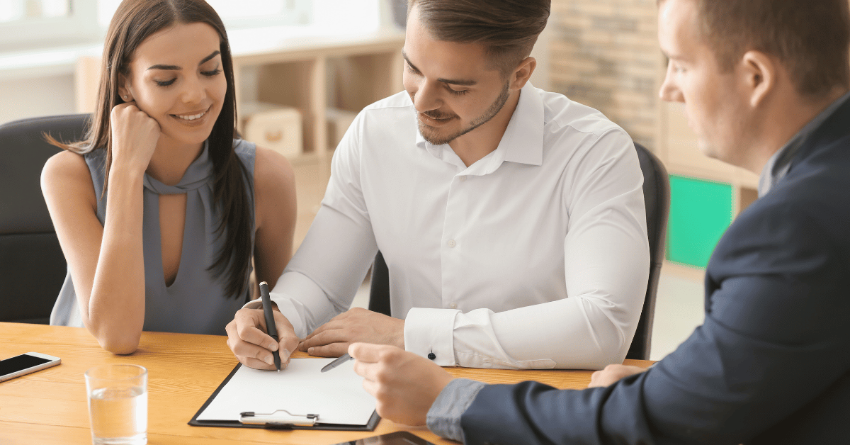 Jeune couple signant un contrat immobilier avec agent